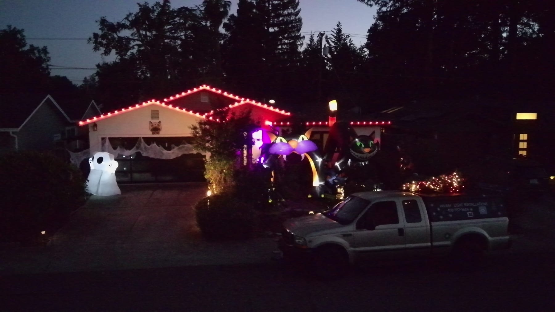 Red roofline lights and purple entry lighting on a house decorated for Halloween