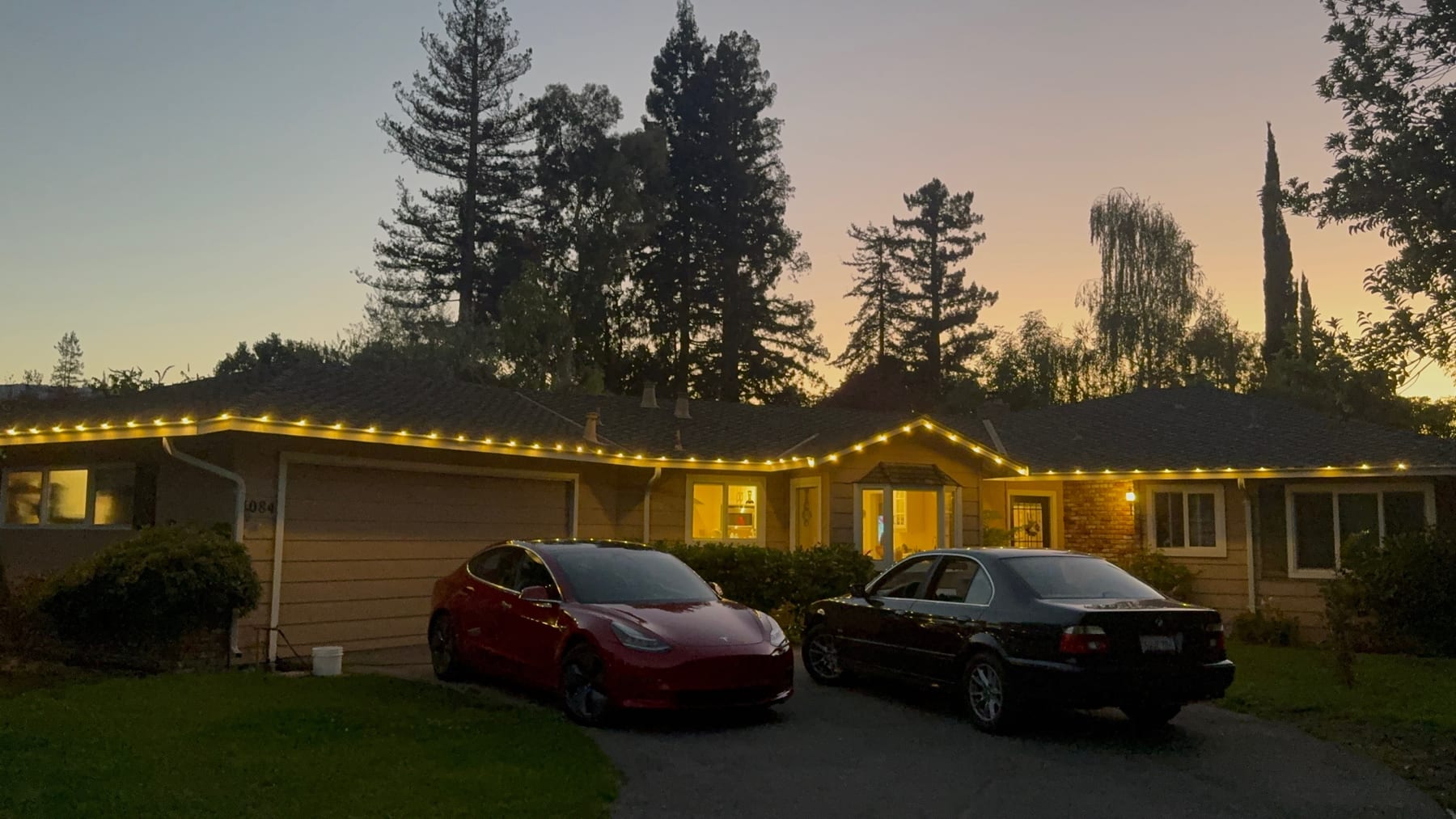 Custom fitted warm-white holiday roofline lights at sunset