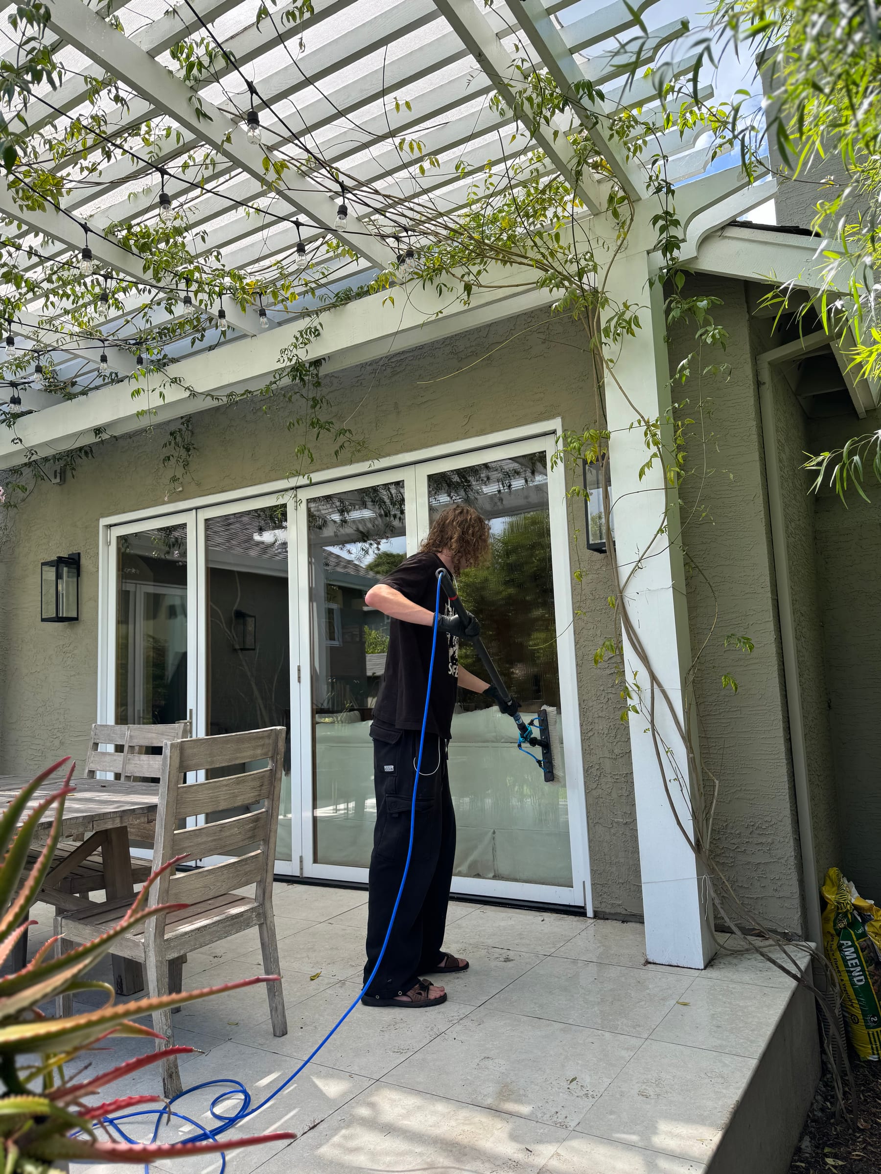 A Bright Blast Teens worker washing windows beneath a pergola